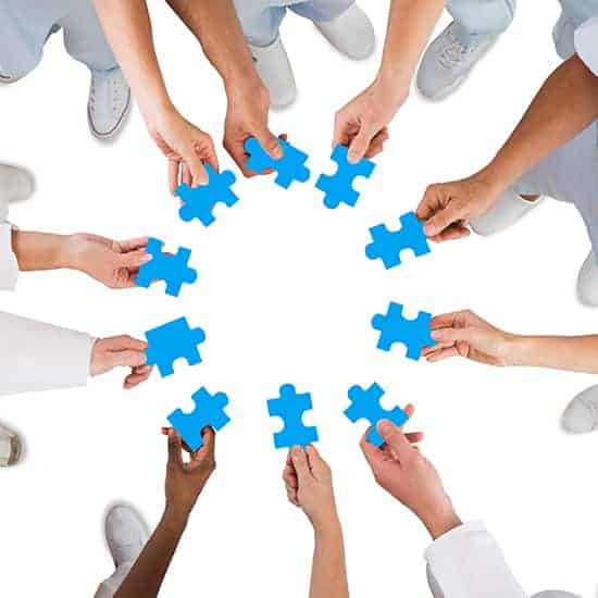 Hände halten Puzzleteile im Kreis und symbolisieren ein Team